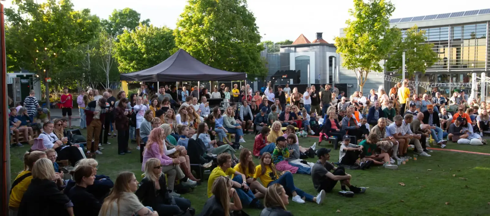 Publikum sidder på græsset til en udendørs koncert ved Klaverfabrikken